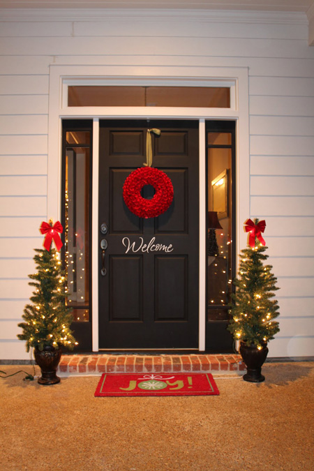 Simple red wreath and lit mini Christmas trees entrance